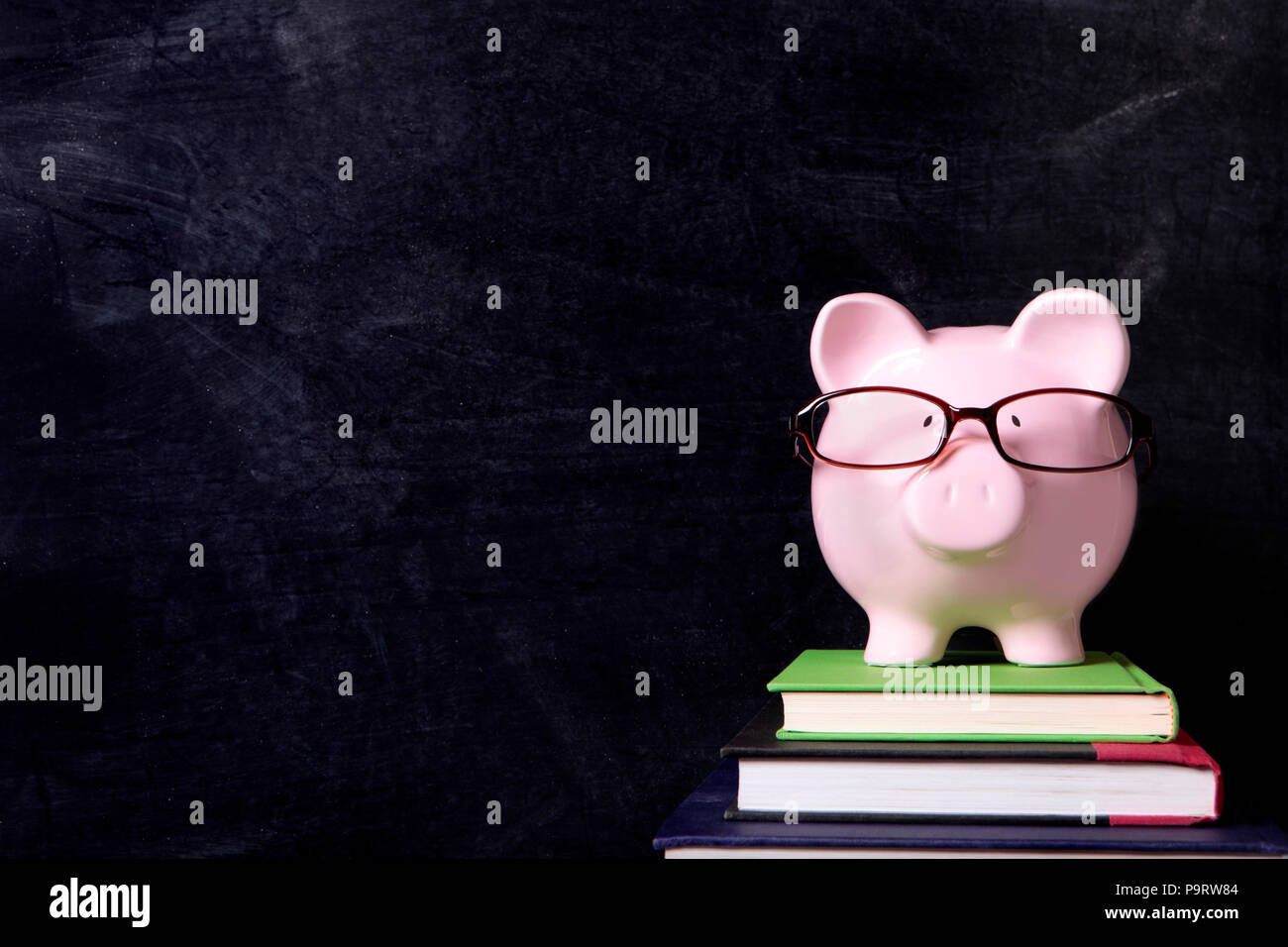 Piggybank con gli occhiali e la lavagna Foto Stock