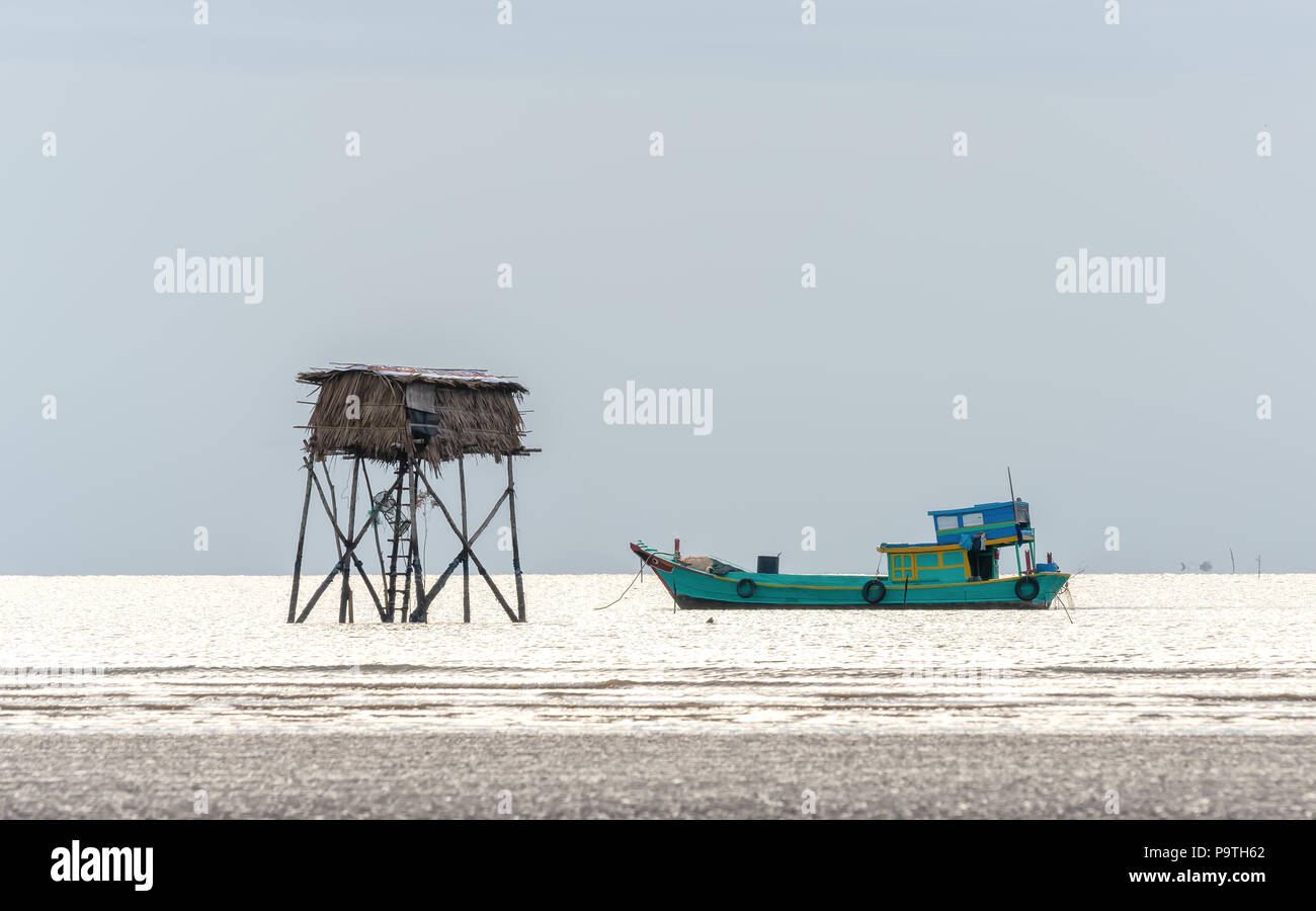 Alba sulla spiaggia con un corpo di guardia accanto alla barca come un mezzo per i pescatori di pesce offerta clam per tutti. Foto Stock