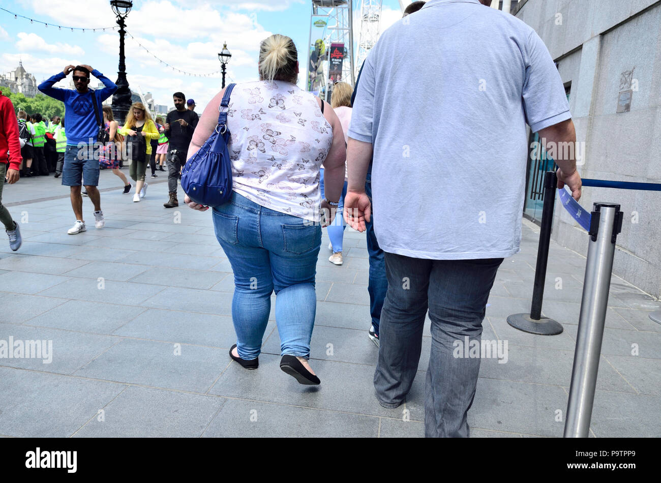Due unidentified sovrappeso / persone obese camminando lungo il South Bank di Londra, Inghilterra, Regno Unito. Foto Stock