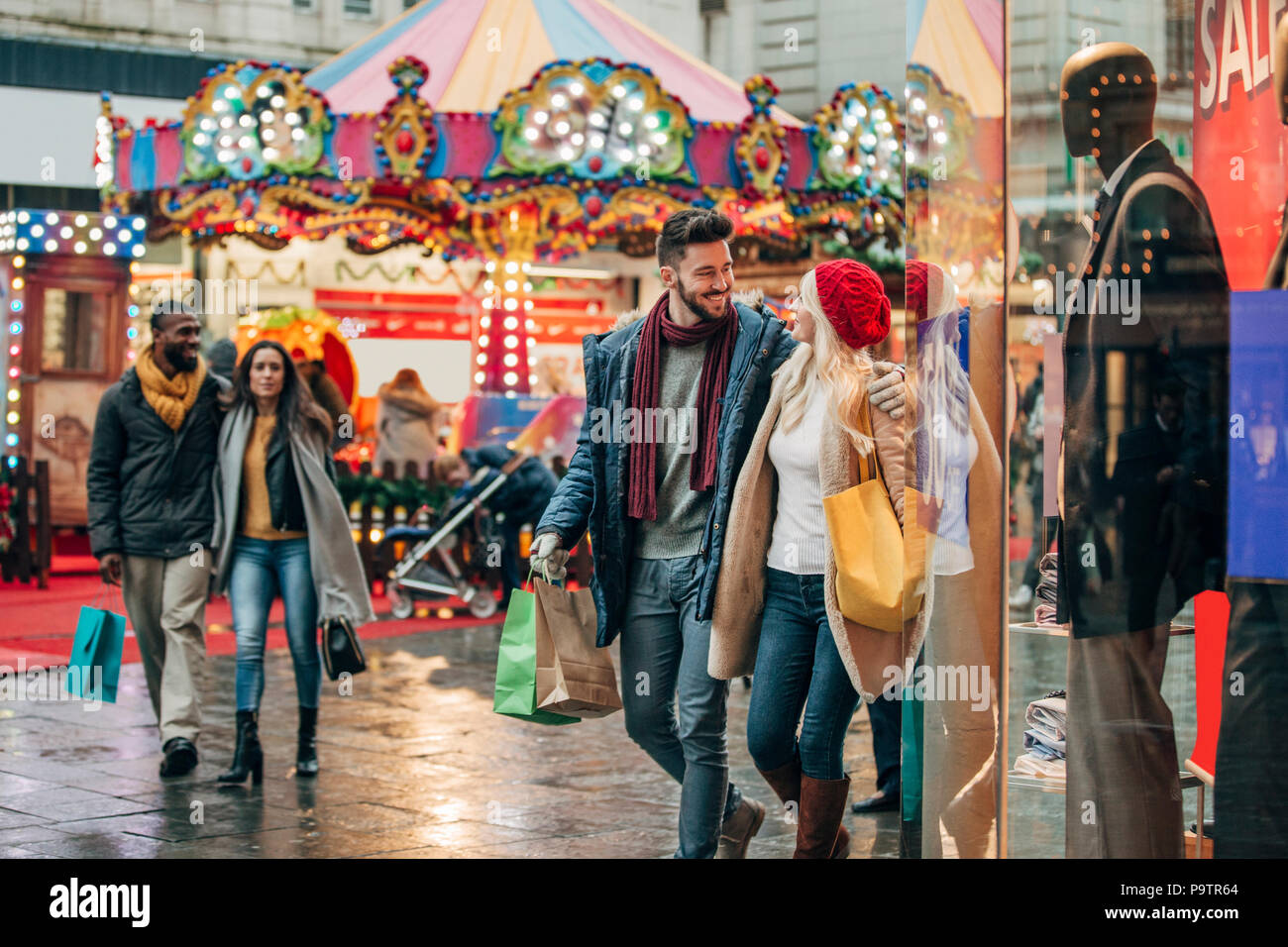 Ampio angolo di visione di due coppie camminando giù per una strada della citta'. Le coppie sono state entrambe shopping nelle vendite. Foto Stock