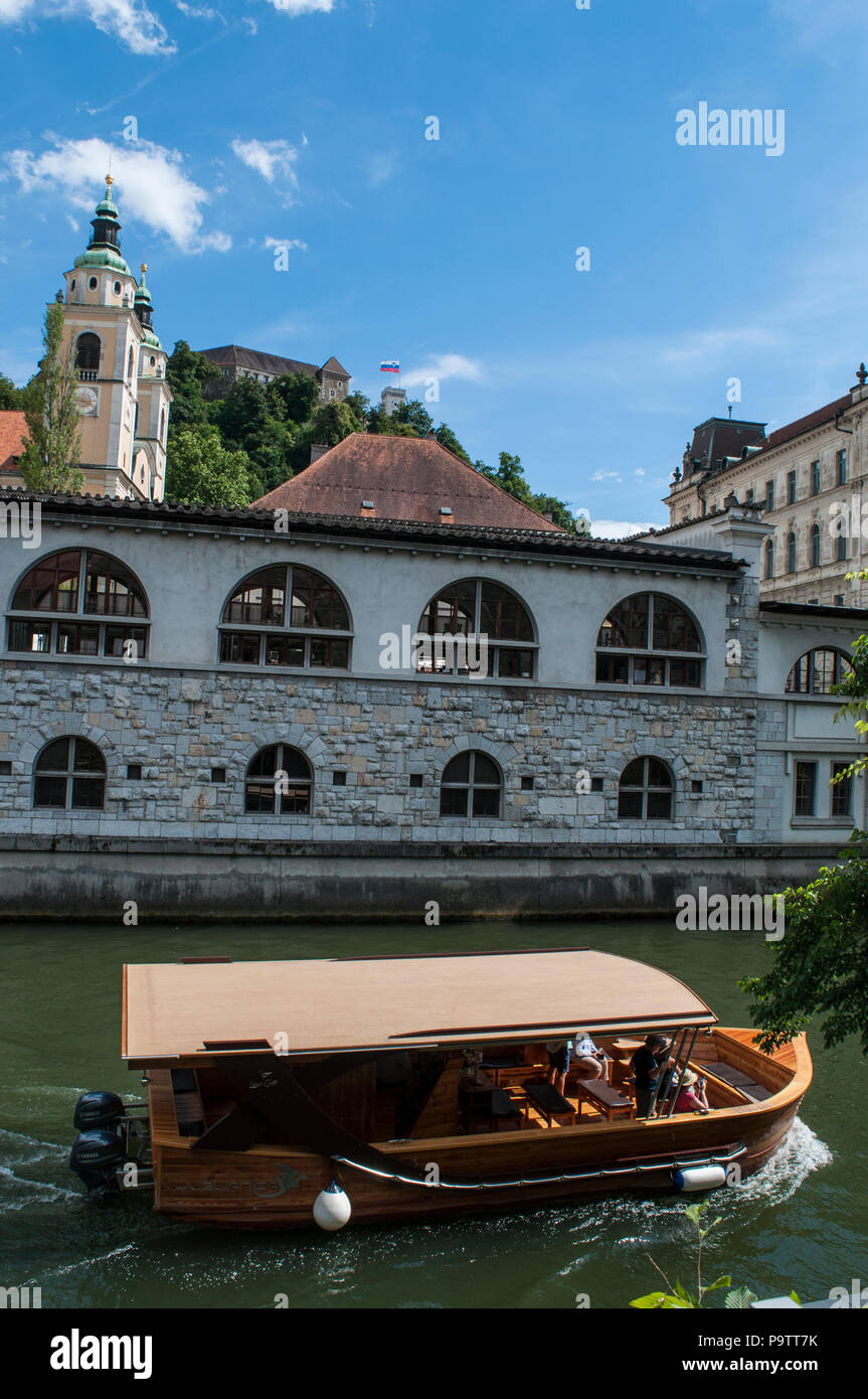 La Slovenia, Europa: egli skyline del centro di Ljubljana con un imbarcazione turistica crociera sul fiume Ljubljanica, conosciuta nel Medioevo come Ljubija Foto Stock