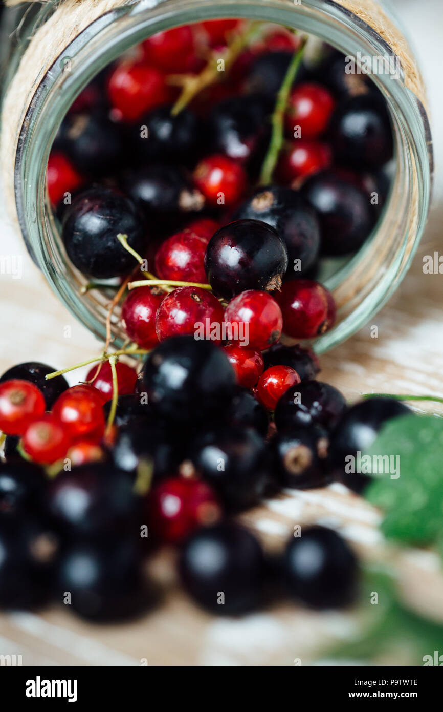 Maturi freschi ribes rosso e nero sullo sfondo di un tavolo di legno. Sfondo di legno Foto Stock