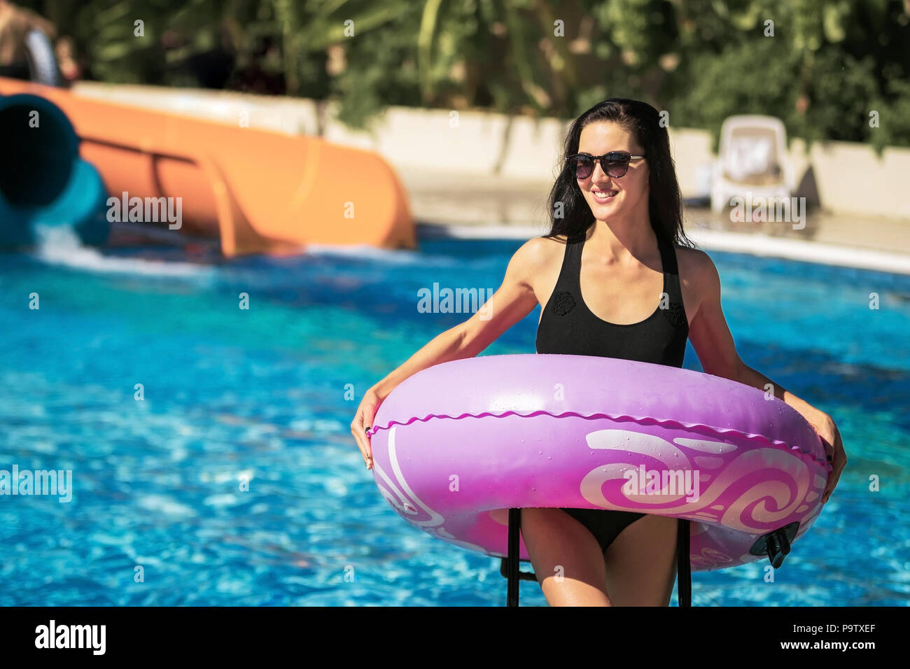 Signora azienda anello di gomma in piedi nella piscina Foto Stock