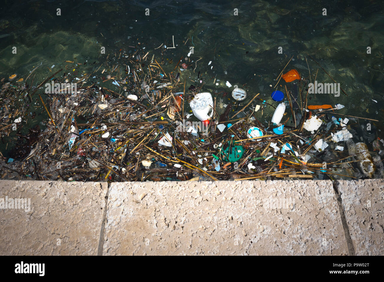 Un paesaggio deprimente vista da una seawall in Croazia che guarda il terribile inquinamento del mare adriatico con galleggiante in plastica in molte forme Foto Stock