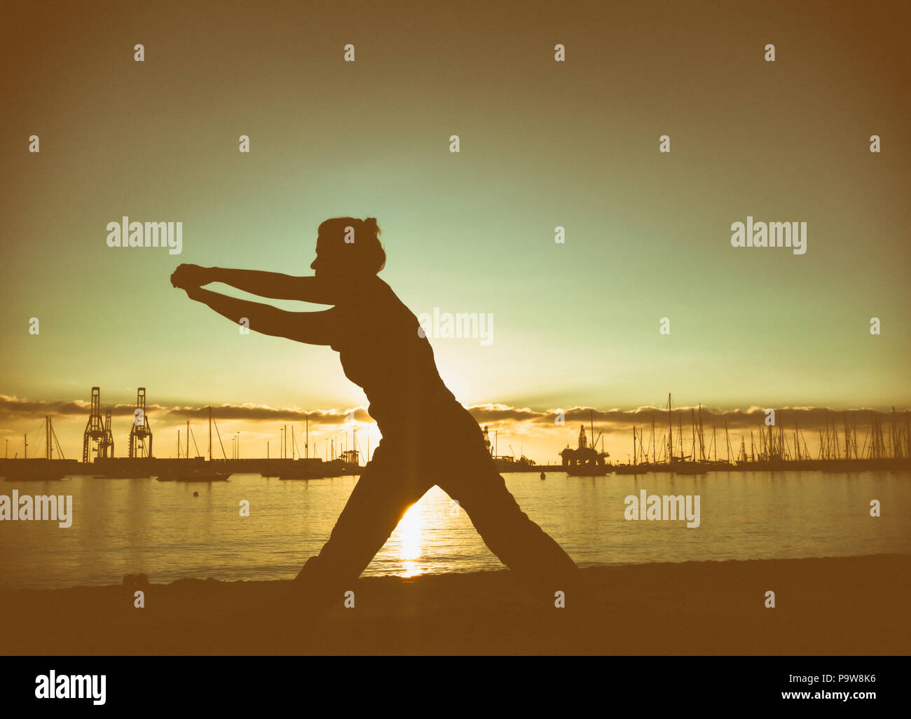 Donna pratica il Tai Chi e Yoga sulla spiaggia della città Foto Stock