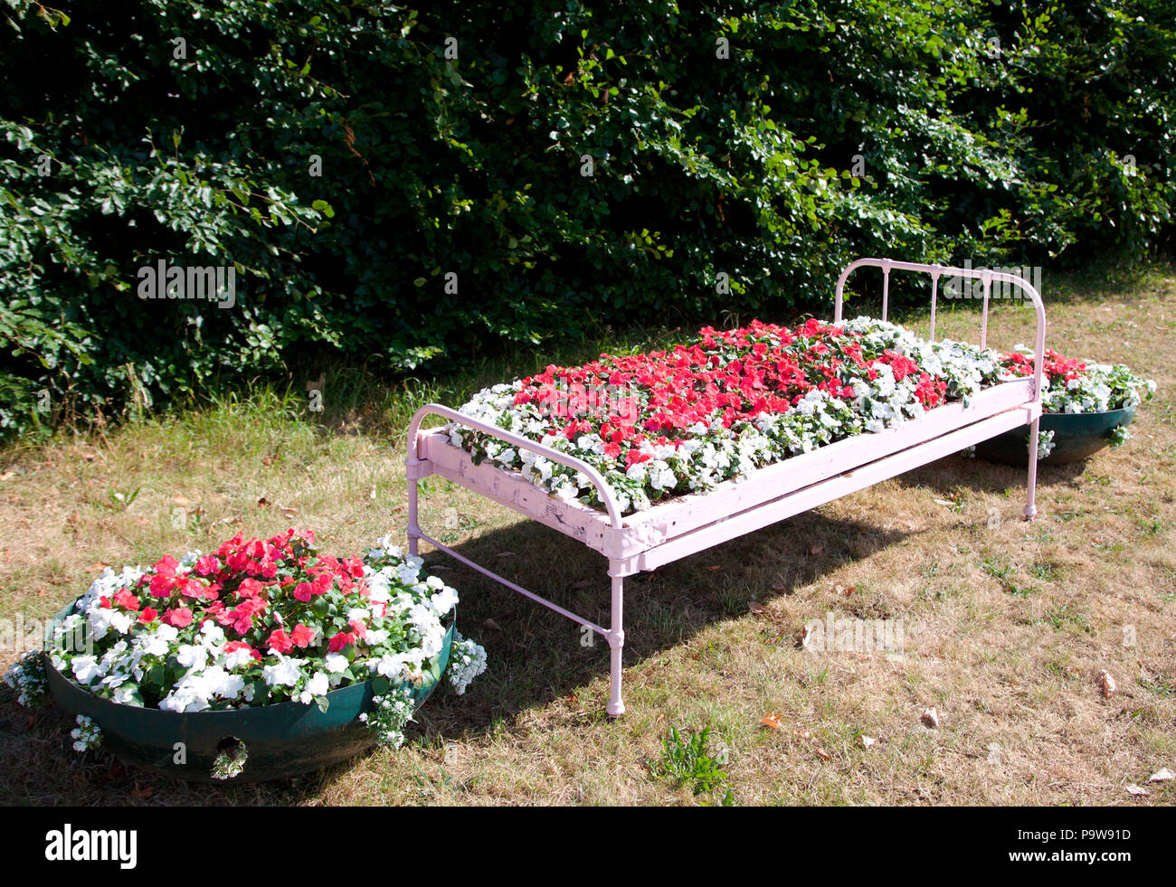 Singola letto di ferro utilizzato come una piantatrice per un estate biancheria dispaly in Carrickmacross Foto Stock