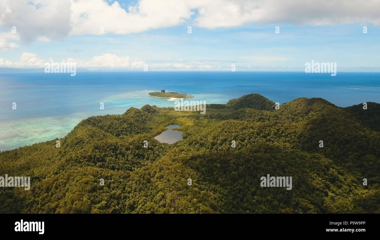 Vista aerea: spiaggia, isola tropicale, Baia Mare e laguna, Siargao. Paesaggio tropicale hill, nuvole e montagne rocce con la foresta pluviale. Acque azzurre della laguna. Paesaggio Shore Bay. Concetto di viaggio. Foto Stock