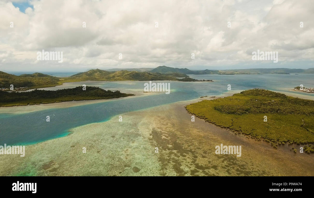 Vista aerea: spiaggia, isola tropicale, Baia Mare e laguna, Siargao. Paesaggio tropicale hill, nuvole e montagne rocce con la foresta pluviale. Acque azzurre della laguna. Paesaggio Shore Bay. Seascape. Concetto di viaggio. Foto Stock