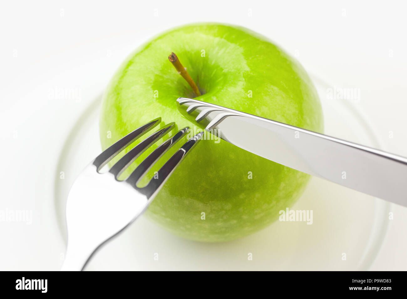 Concetto di dieta, mela verde su una piastra bianca, forcella, coltello, donna c Foto Stock