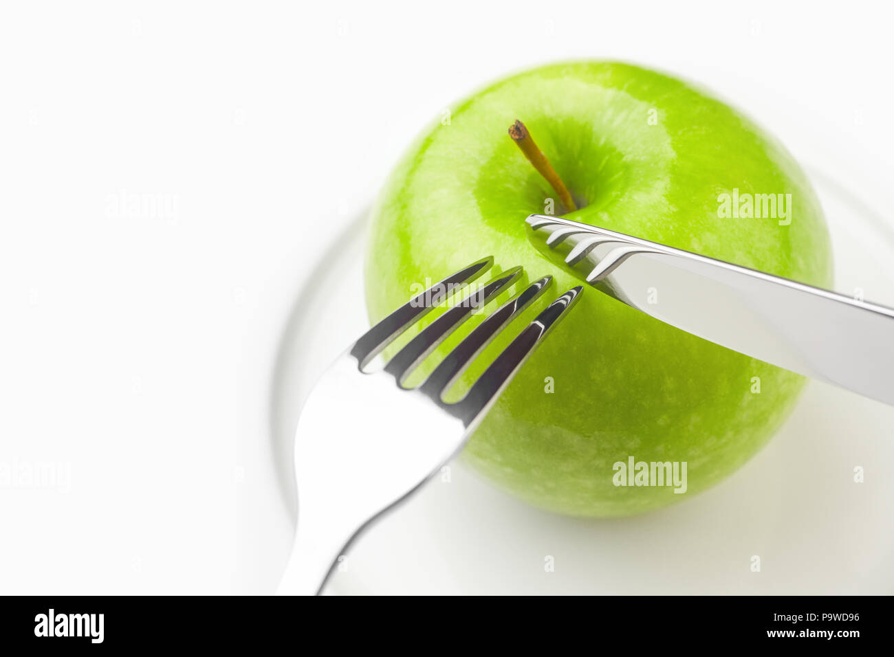 Concetto di dieta, mela verde su una piastra bianca, forcella, coltello, donna c Foto Stock