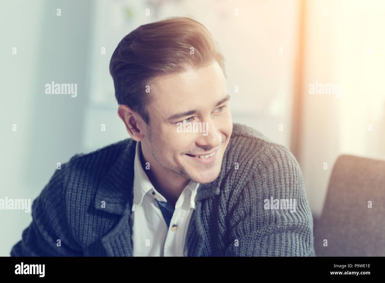Express positività. Felice persona maschio mantenendo il sorriso sul suo viso e testa di tornitura mentre è seduto al suo gabinetto Foto Stock