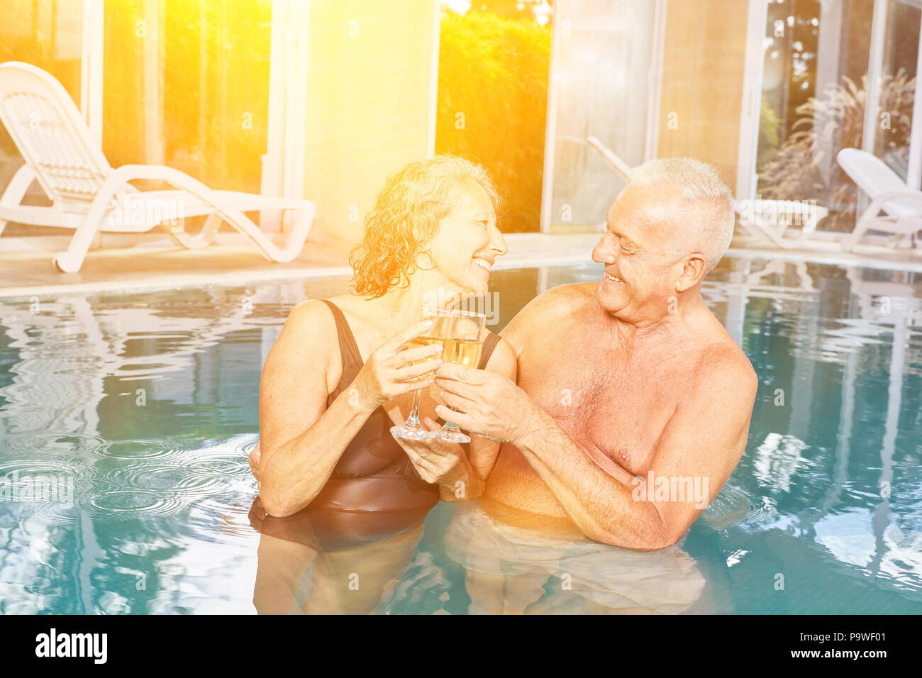 Coppia senior di bere champagne presso l'hotel piscina durante una vacanza termale Foto Stock