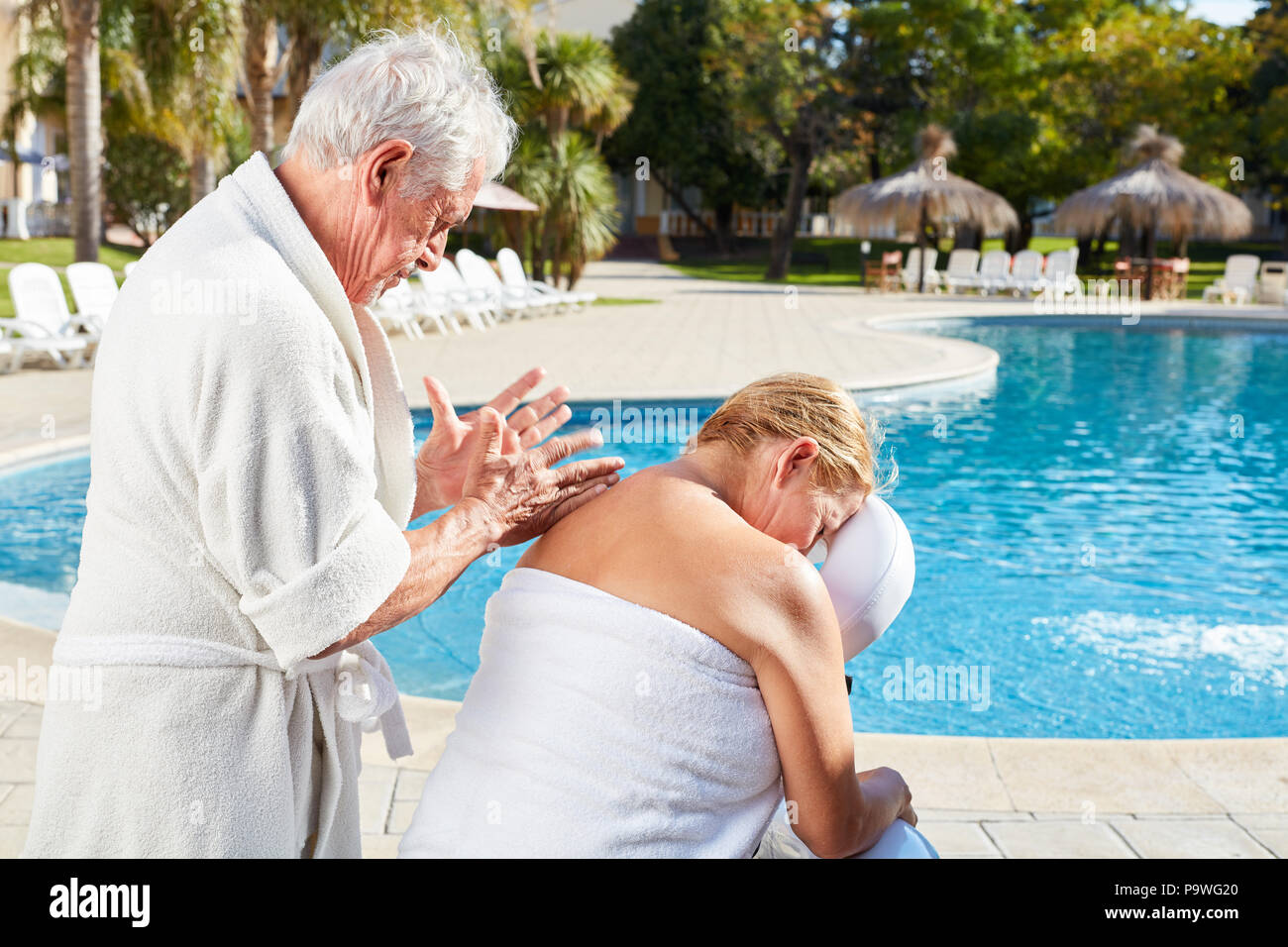 Senior donna ottiene massaggio alla schiena in vacanza benessere dalla piscina Foto Stock