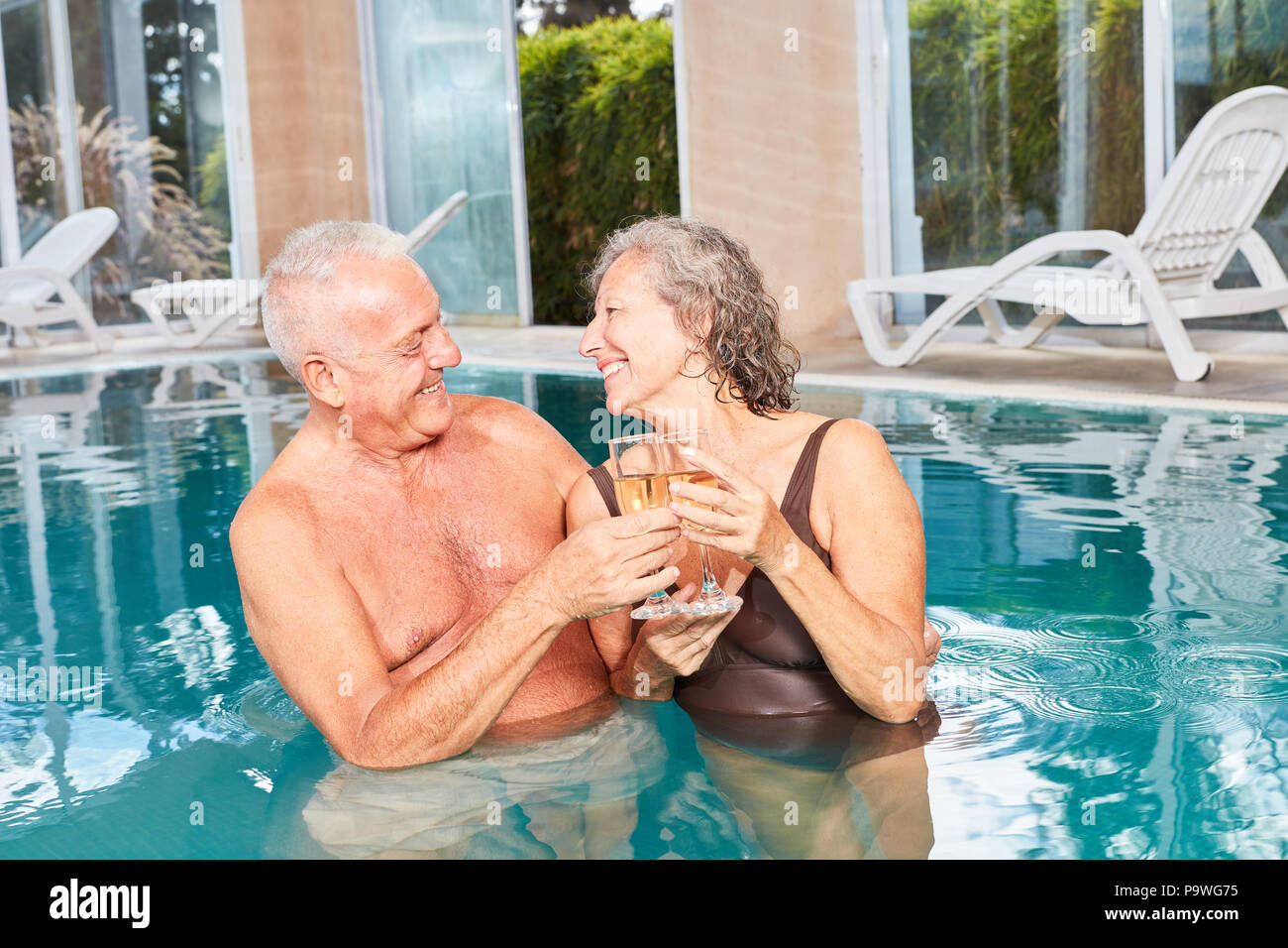 Matura in amore per gli anziani di bere champagne insieme nella piscina dell'Hotel Benessere Foto Stock