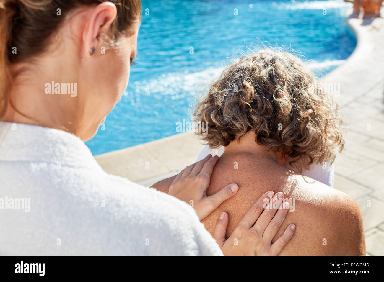 Fisioterapista massaggiare la schiena di una donna senior presso la piscina nel spa hotel Foto Stock