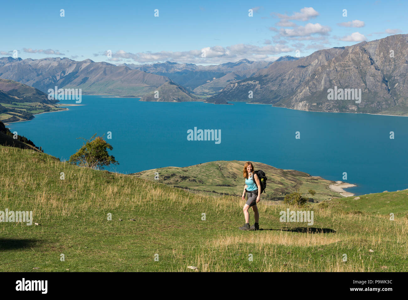 Escursionista femmina a picco istmo via, Lago Hawea e panorama di montagna, Otago, Isola del Sud, Nuova Zelanda Foto Stock