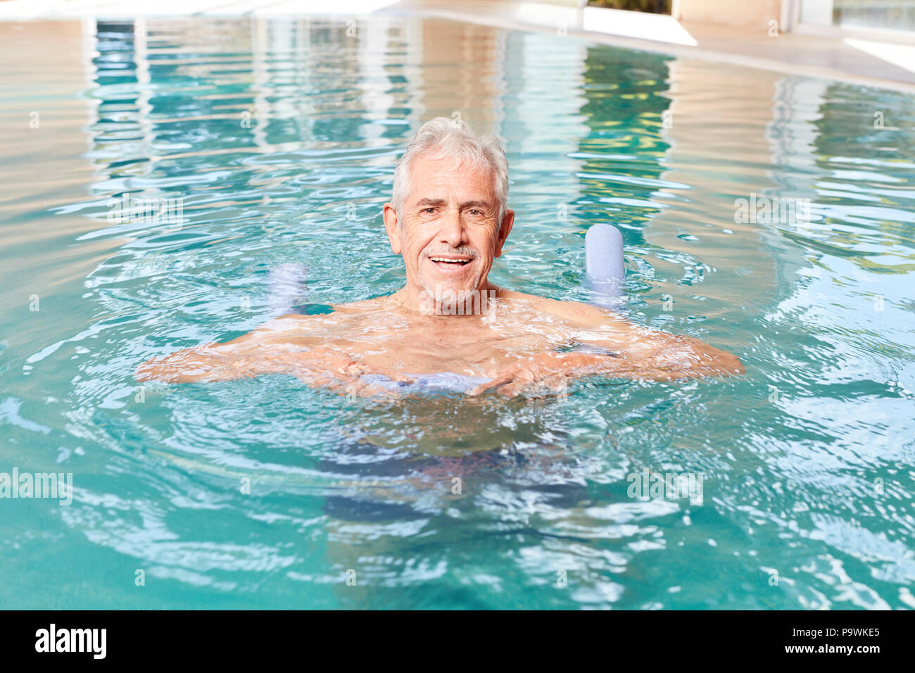 Senior vitale l uomo impara a nuotare in piscina con swim noodle nella spa Foto Stock