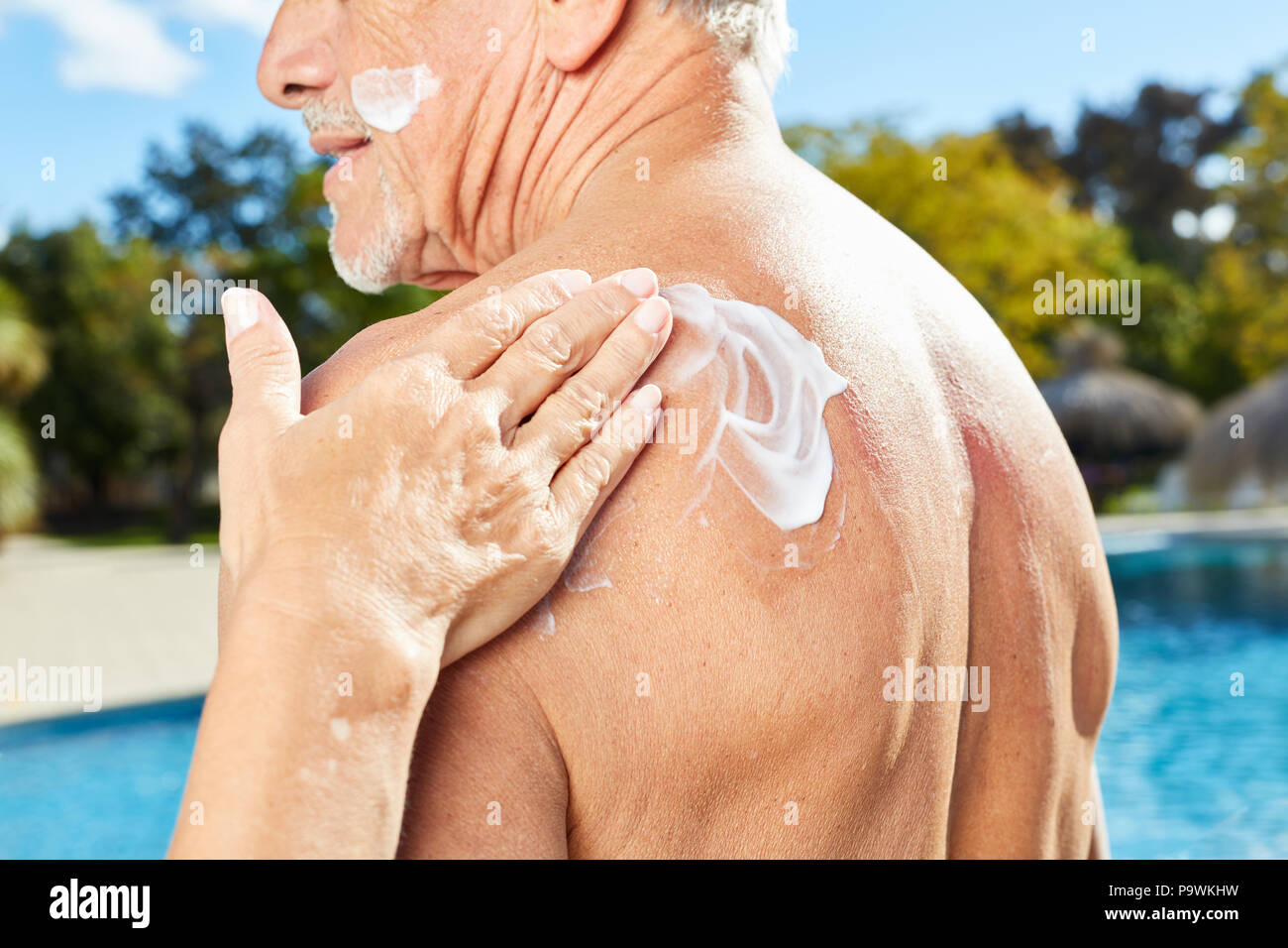 Donna sfrega contro un uomo con la schiena con sunscreen come filtro solare Foto Stock
