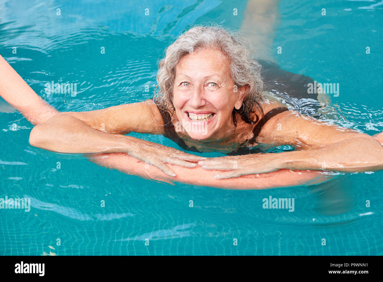 Felice vitale donna senior è imparare nuotare con l aiuto di nuoto in piscina Foto Stock