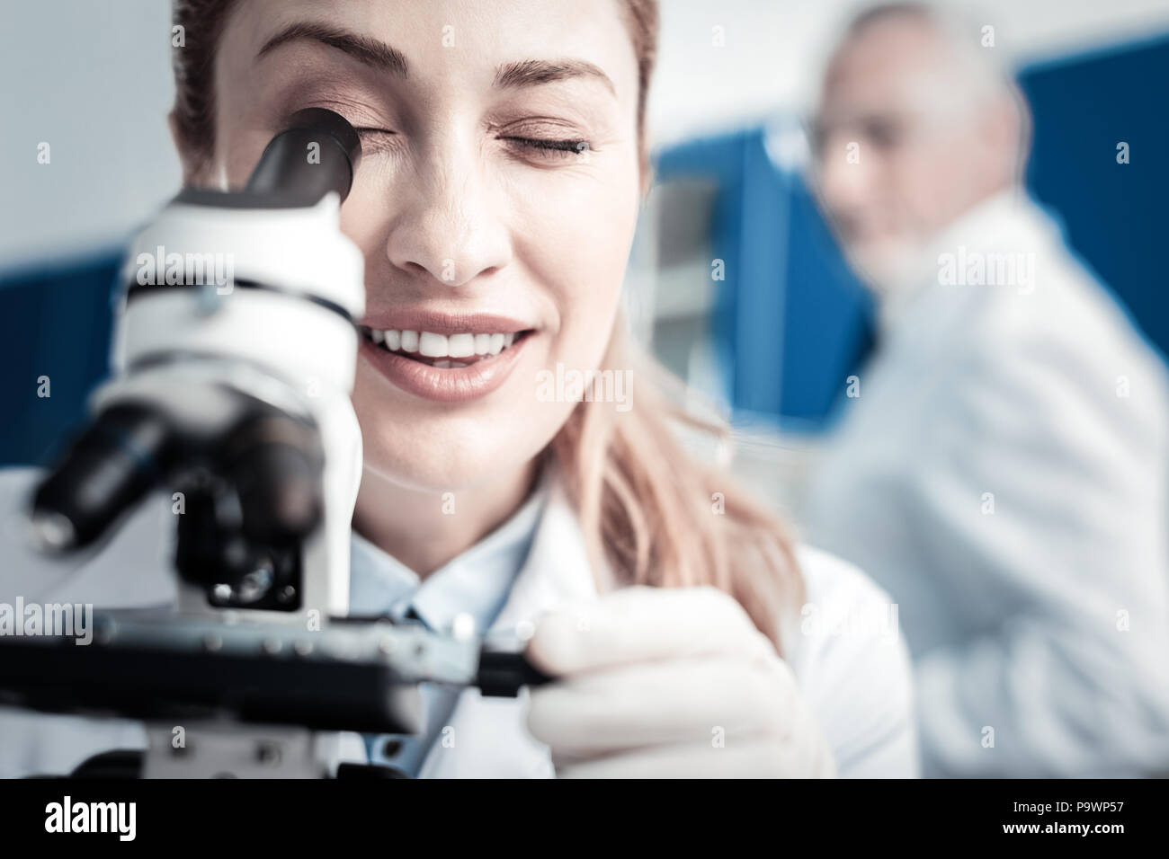 Ritratto di un positivo donna scienziato cercando nel microscopio Foto Stock