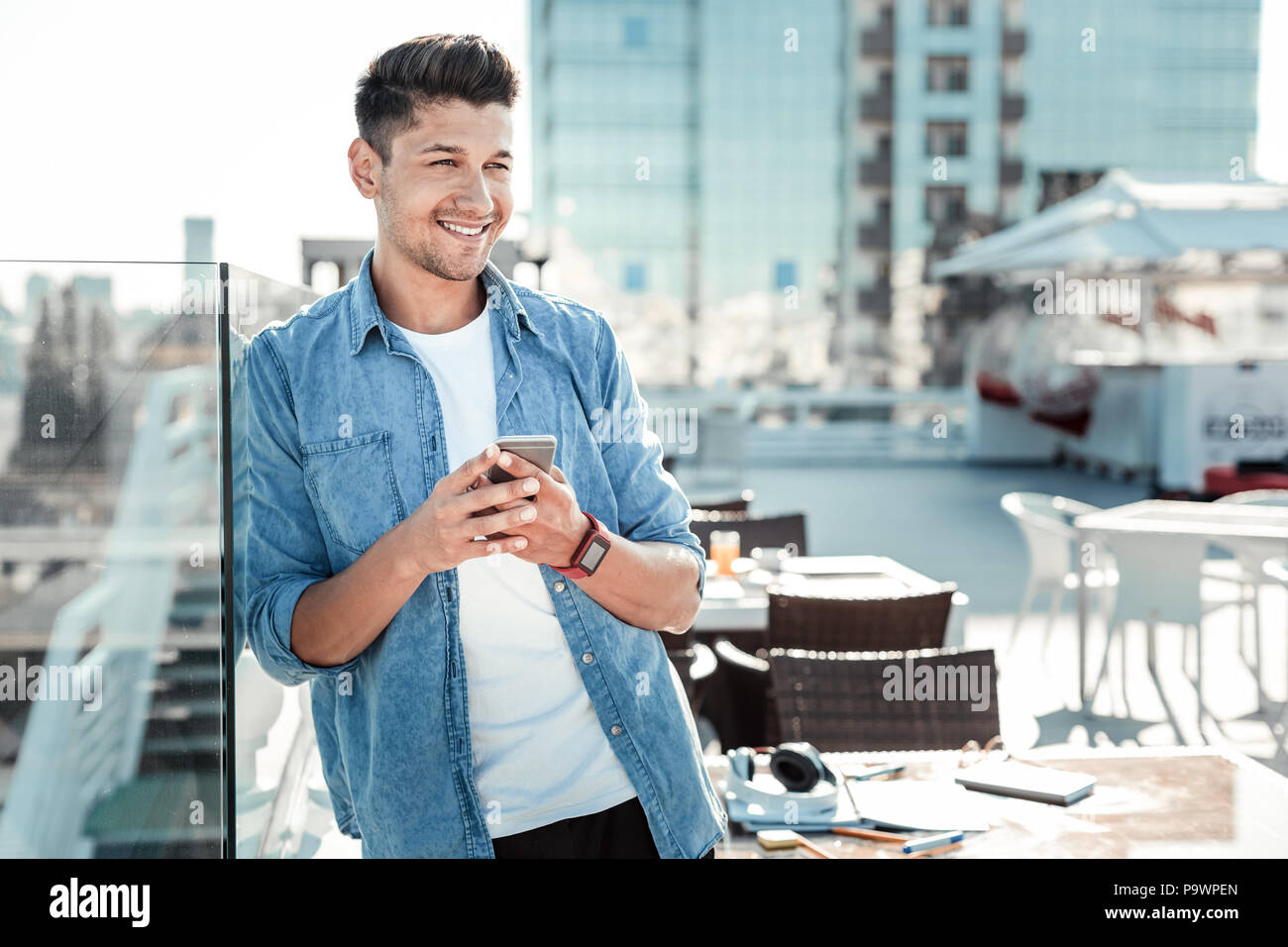 Allegro giovane uomo appoggiato sulla parete di vetro Foto Stock