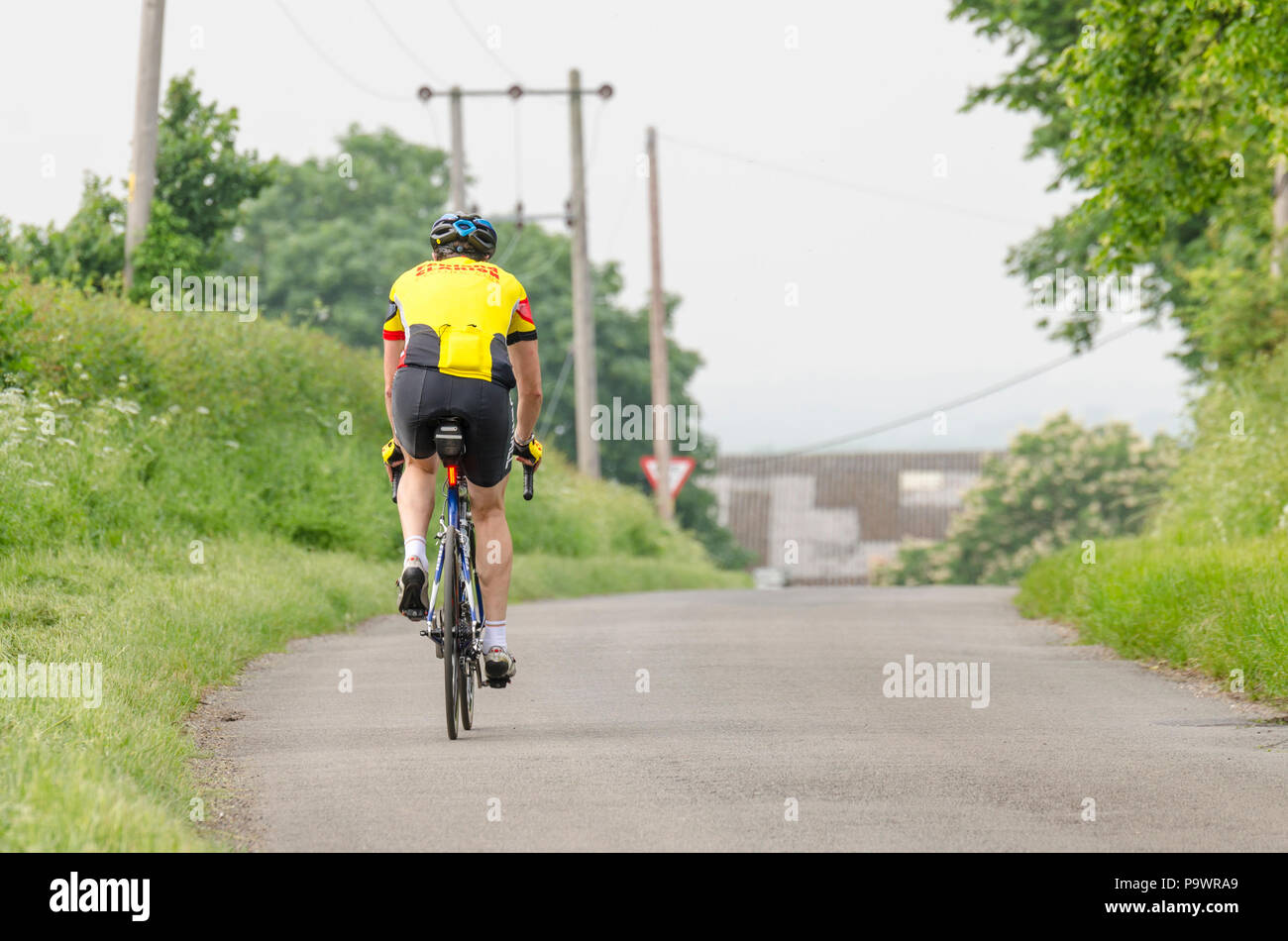 Ciclista maschio ciclismo su uno stretto vicolo del paese in Inghilterra, Regno Unito Foto Stock