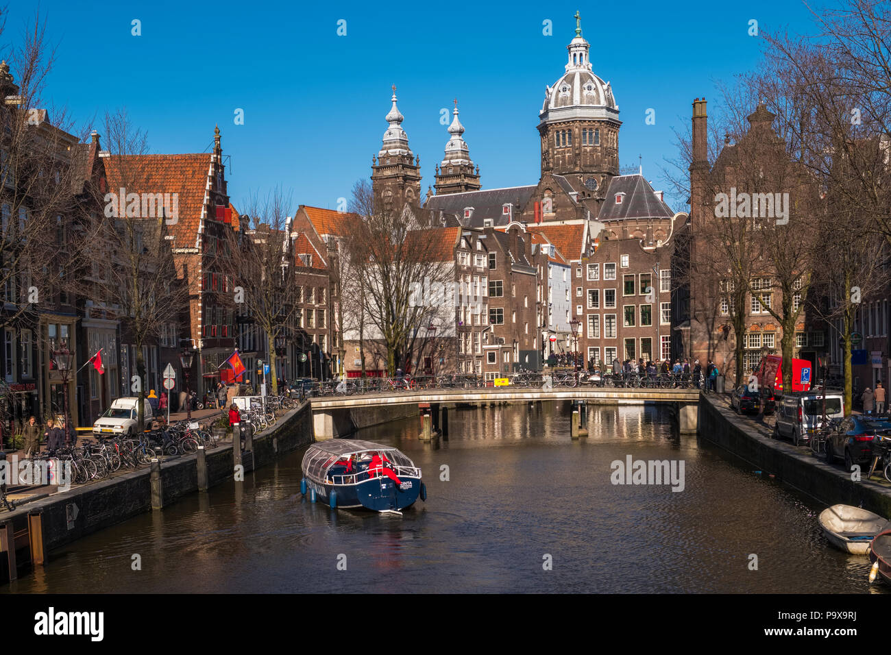 Molte le biciclette su un ponte che si affaccia sul canale di Amsterdam, in Olanda, in Europa con un piacere in barca a vela al di sotto Foto Stock