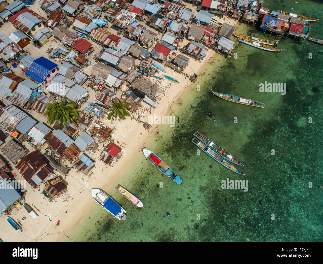 Un drone foto guardando in giù su un pessimo Bajau zingari del mare village e beach, barche e poco profonde acque tropicali, a Mabul Island, Sabah, Malaysia. Foto Stock