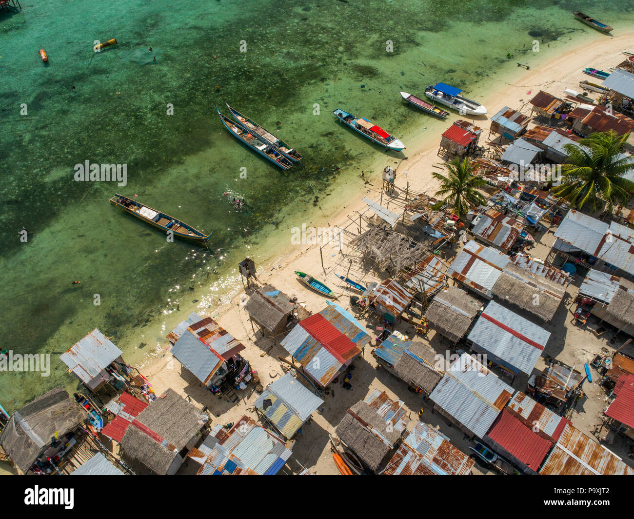 Un drone foto guardando in giù su un pessimo Bajau zingari del mare village e beach, barche e poco profonde acque tropicali, a Mabul Island, Sabah, Malaysia. Foto Stock