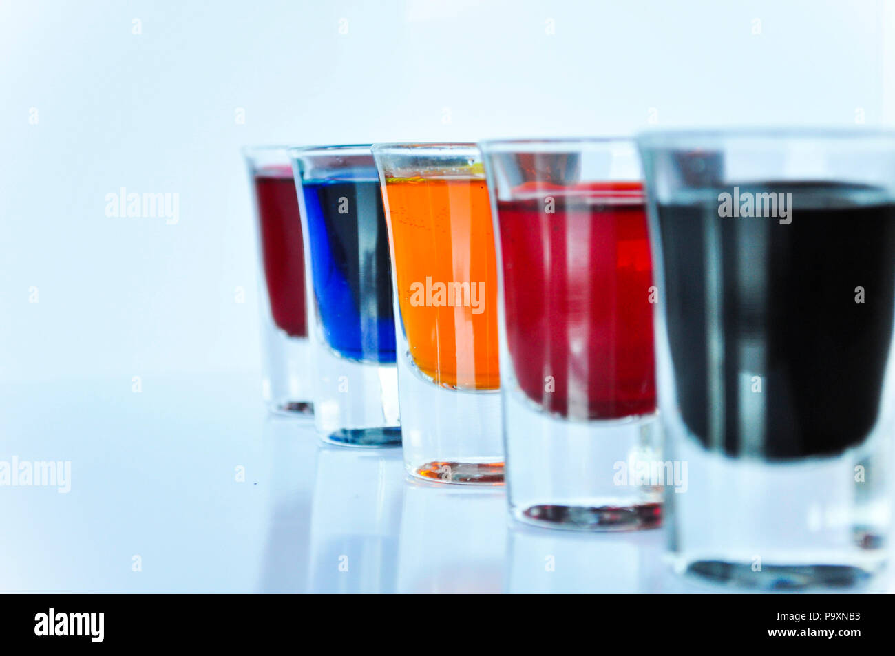 Cinque bicchieri riempiti con liquidi di diversi colori su sfondo bianco Foto Stock
