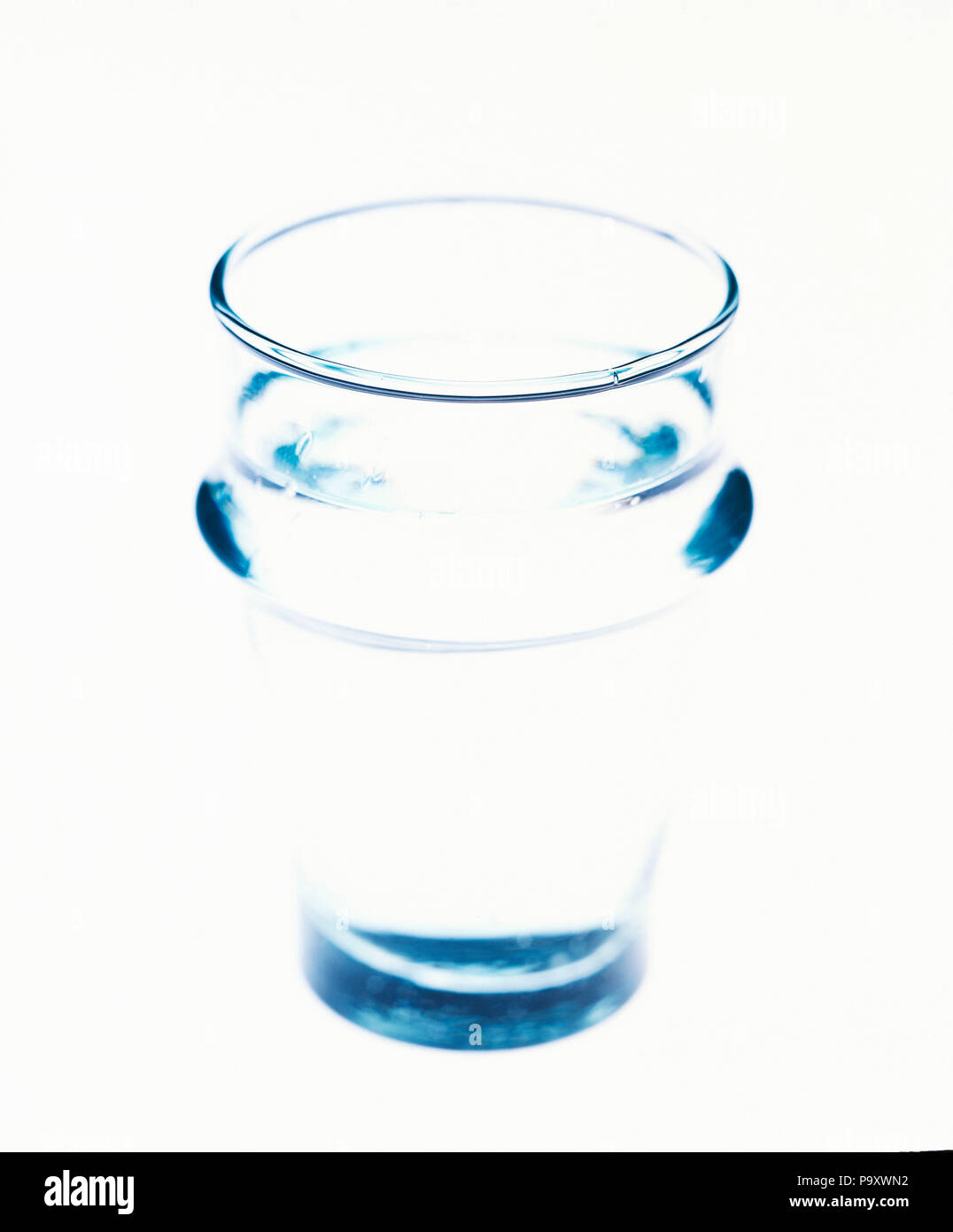 Molto trasparente bicchiere di acqua su uno sfondo bianco Foto Stock