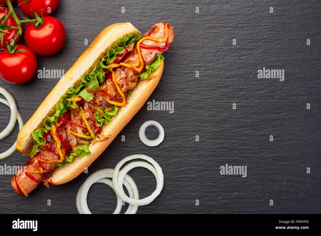 Succosa di hot dog e ingredienti su di ardesia scura Foto Stock