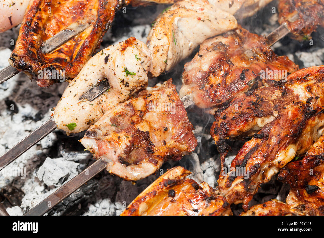 Orange succosi pezzi di carne durante la cottura maggiore Caucaso kebab su spiedini su un fuoco. Camping. La foto è stata scattata da vicino, piccole profondità di campo Foto Stock