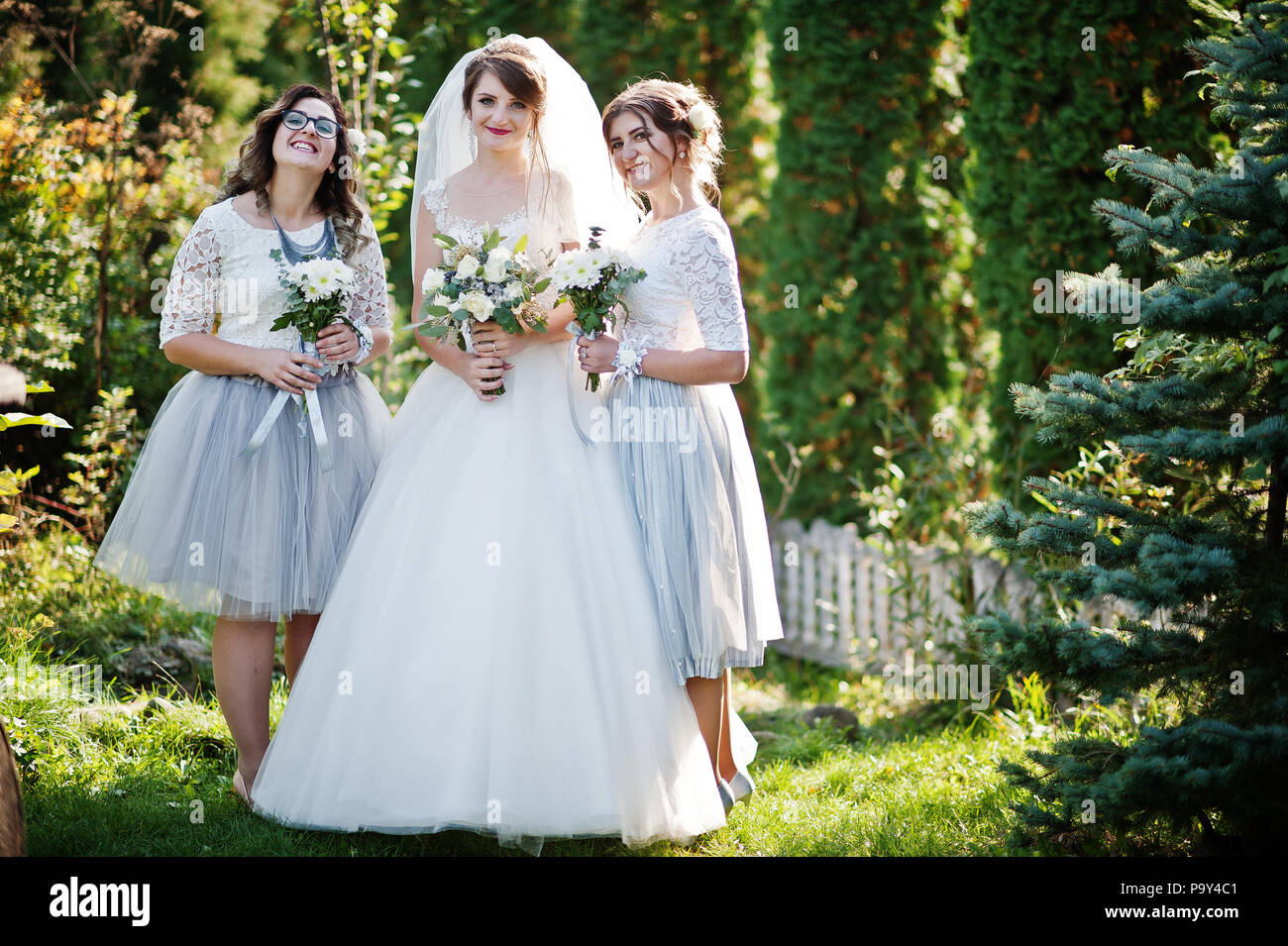 Felice sposa in posa con le sue damigelle outdoor con mazzi. Foto Stock