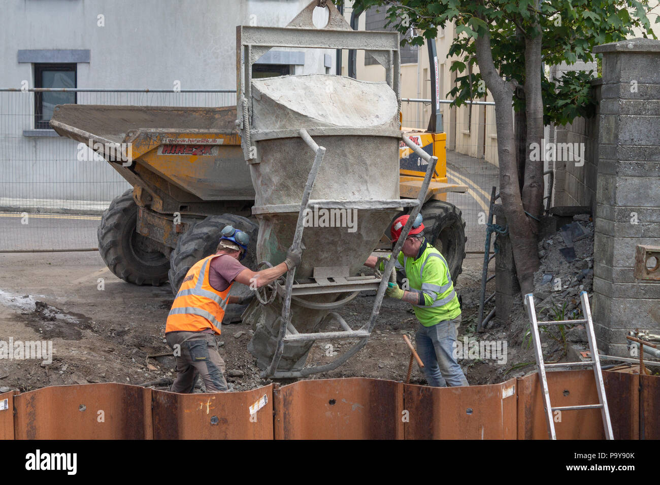 Costruttori la colata di cemento in cassaforma metallica da una tramoggia ribaltabile a mediante la gru. Foto Stock