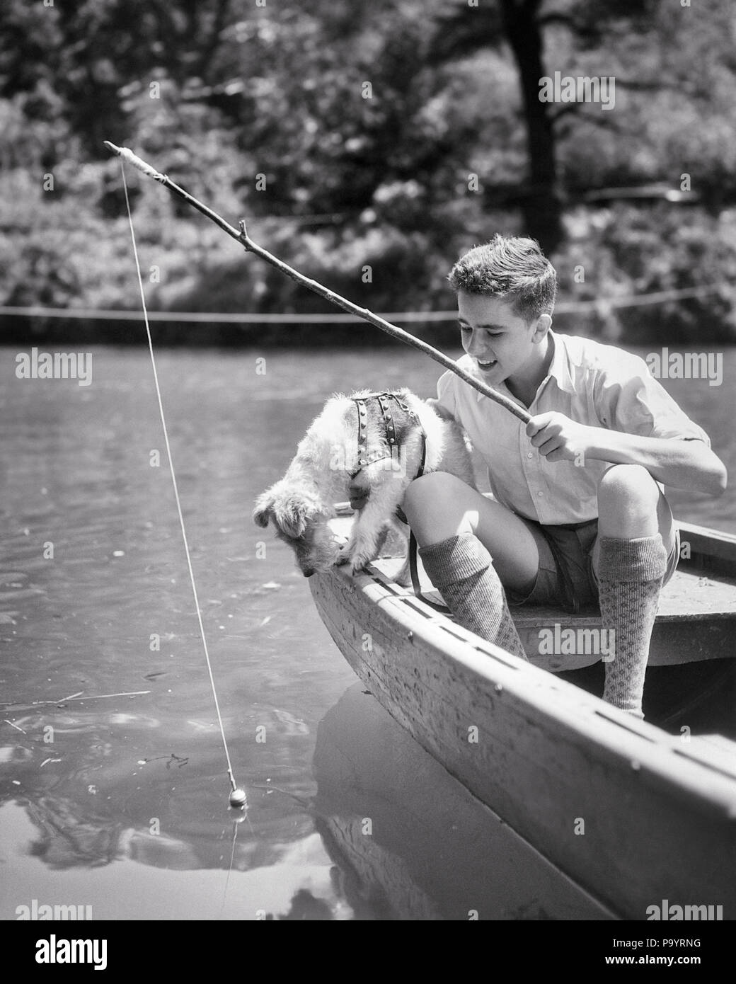 1930s PAZIENTE PRETEEN BOY e speranzosi CANE LA PESCA INSIEME IN canotto su stagno PUP attentamente guardare BOBBER FLOTTAZIONE - un5125 HAR001 HARS GANCIO B&W ESTATE cattura la felicità dei mammiferi e i canini emozione speranzosi in attesa nella sul canotto PRETEEN POOCH galleggiante supporto soleggiato canine novellame mammifero pre-teen pre-teen BOY PUP RELAX PRIMAVERA convivere in bianco e nero di etnia caucasica HAR001 in vecchio stile Foto Stock