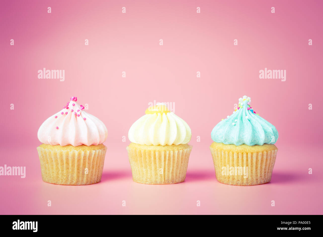 Tre mini cupcake Fantasia su sfondo rosa, toni pastello Foto Stock