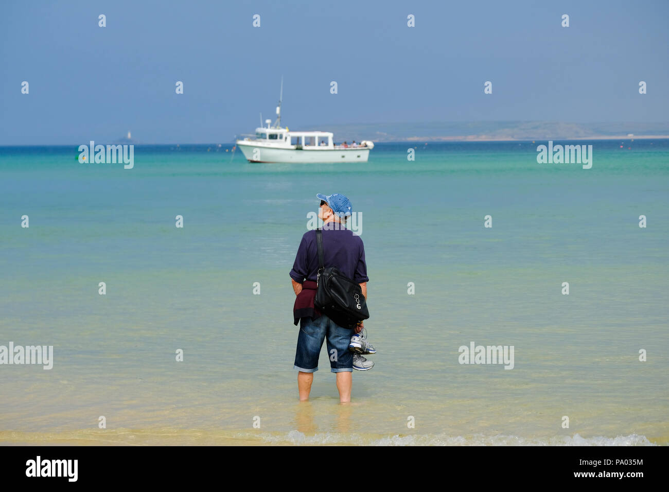 L'uomo paddling in acque poco profonde sulla spiaggia di St Ives in Cornovaglia Foto Stock