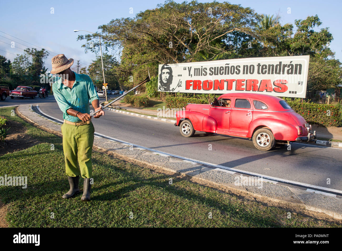 A piena lunghezza shot dell'uomo prato di taglio sulla strada, Pinar del Rio, Cuba Foto Stock