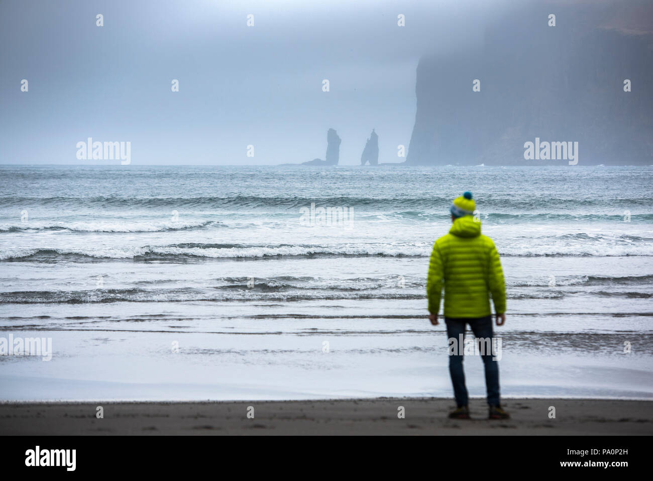 Vista posteriore dell'uomo in piedi sulla riva del mare, delle Isole Faerøer, Danimarca Foto Stock