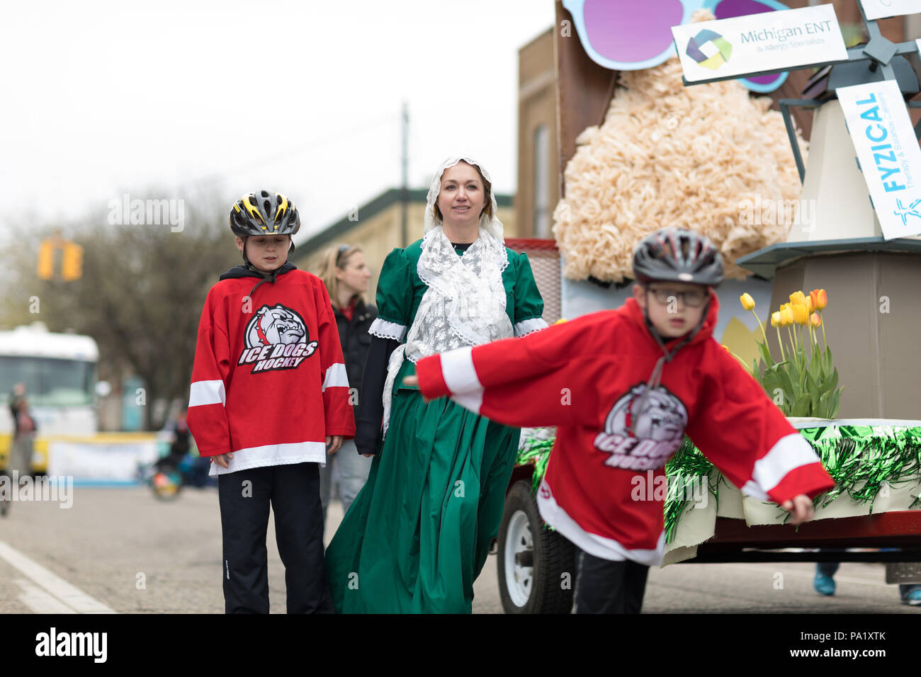 Holland, Michigan, Stati Uniti d'America - 12 Maggio 2018 donna che indossa abiti tradizionali e i bambini con i cani Ice Hockey shirts andando giù per la strada al Muziek Pa Foto Stock
