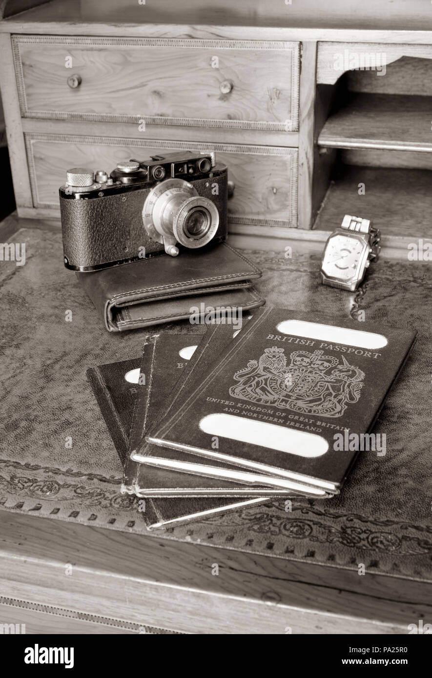 Antica scrivania con passaporti e vecchia leica fotocamera, guarda con nomi tranciati Foto Stock