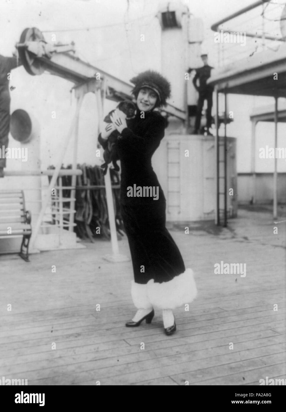 . Inglese: Annette Kellerman e a piena lunghezza verticale, in piedi sul ponte della nave, rivolto verso la parte anteriore, tenendo un nero pug dog (convertito da tif a jpg prima di caricare, ritagliata per rimuovere il confine e un segmento del ponte di vuoto nella parte inferiore della foto per inquadrare meglio la materia.) . circa 1914 133 AnnetteKellermanShipDog Foto Stock
