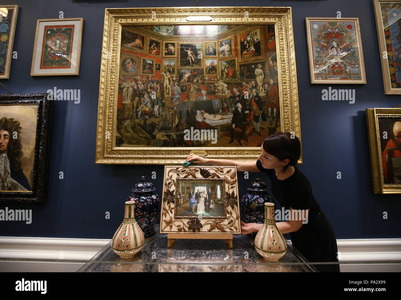 Un dipendente della Royal Collection Trust che spolverò la cornice di una fotografia della Royal Family, con dipinto a olio la Tribuna degli Uffizi, 1772-7, di Johann Zoffany, appeso sopra durante un'anteprima della mostra Prince & Patron nella Sala della cena di ballo a Buckingham Palace, Londra. Foto Stock