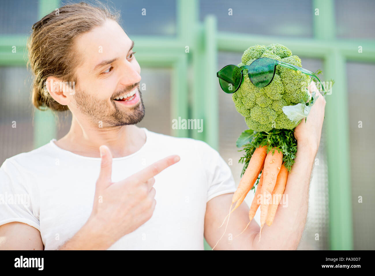 Divertente ritratto di un uomo con il suo amico vegetale fatta di broccoli e carote. Mangiare sano concetto Foto Stock