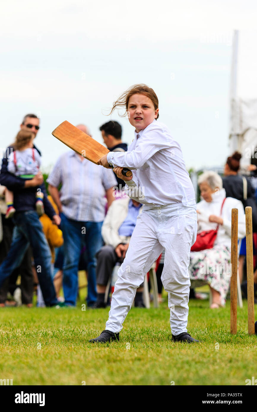 Ragazza giovane, bambino, 12-13 anni, battere con il cricket bat mentre vestito in costume vittoriano durante la partita di cricket. Broadstairs Dickens week festival Foto Stock