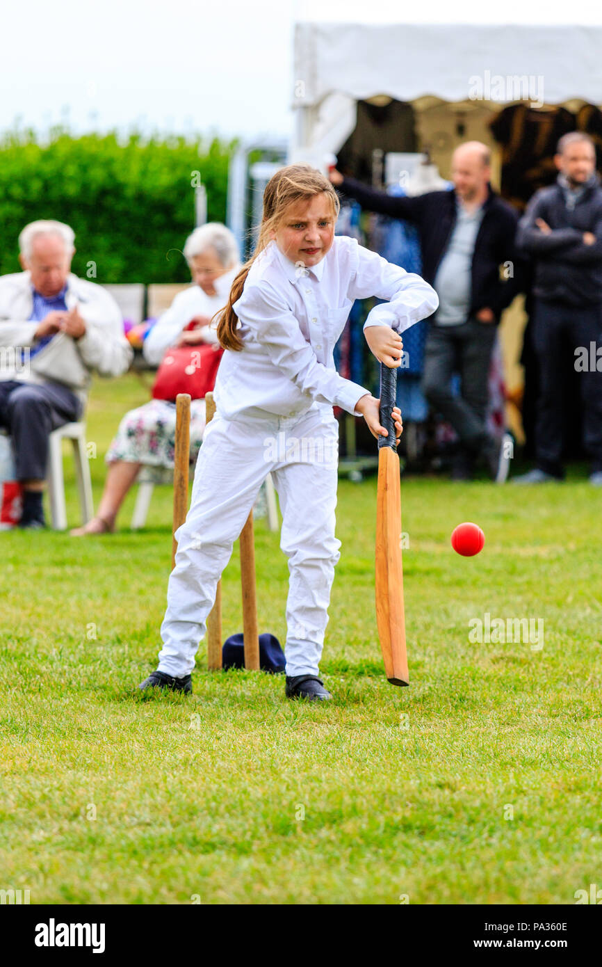 Ragazza giovane, bambino, 12-13 anni, battere con il cricket bat mentre vestito in costume vittoriano durante la partita di cricket. Broadstairs Dickens week festival Foto Stock