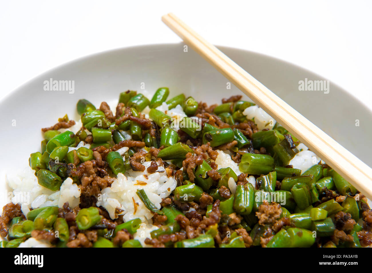 Ciotola di carne bovina macinata spezzatino con fagioli rotonda servita con riso bollito con bacchette su sfondo bianco Foto Stock