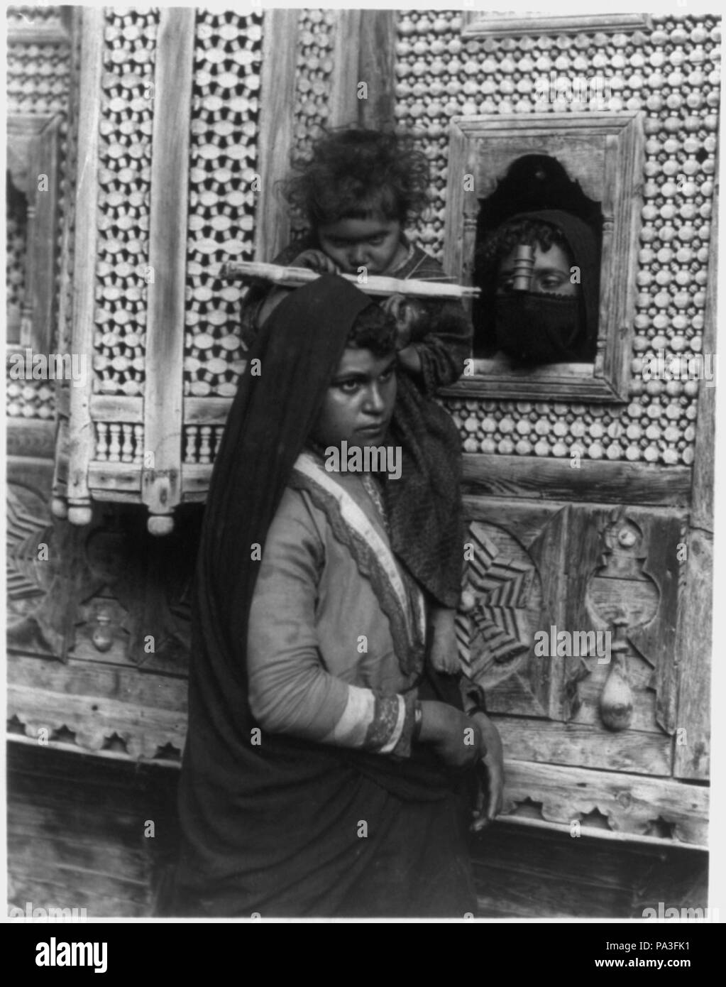 305 Bambino, che è cieca da un occhio, seduto sulla spalla della donna e succhiare canna da zucchero; e la testa di un'altra donna che guarda attraverso la finestrella, Egitto LCCN2001705646 Foto Stock