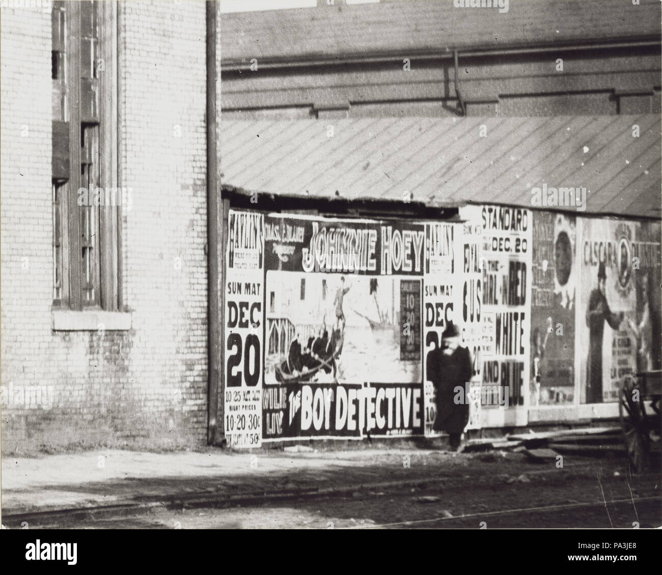 84 Un uomo cammina davanti ad una parete del poster pubblicitari tra cui uno per Johnnie Hoey il ragazzo Detective a giocare a Havlin's Theatre a 600 Walnut Street Foto Stock